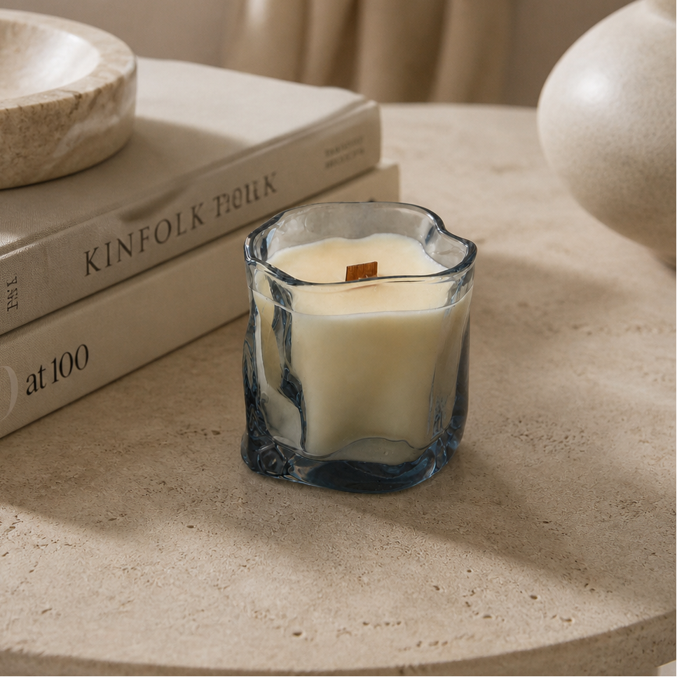 Vela aromática de soja en frasco de cristal irregular azul en ambiente decorativo