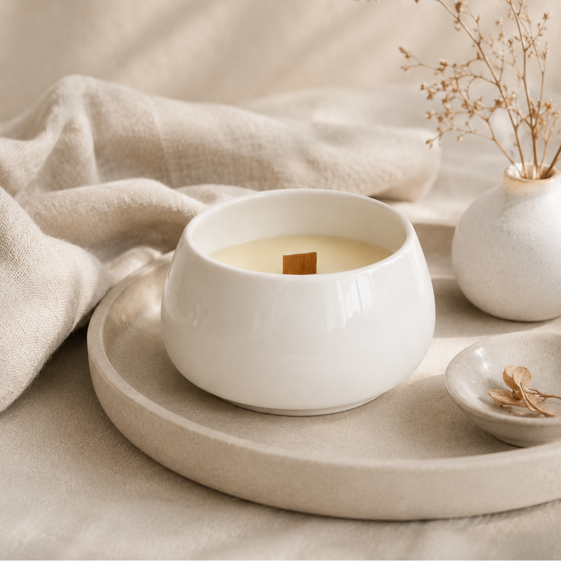 Vela aromática de soja en cuenco de porcelana blanca sobre bandeja decorativa