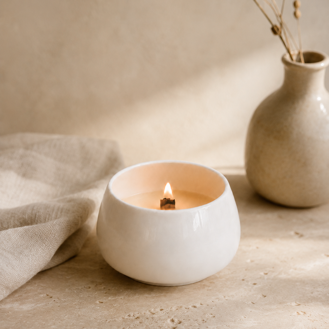 Vela aromática de soja en cuenco de porcelana blanca encendida con mecha de madera