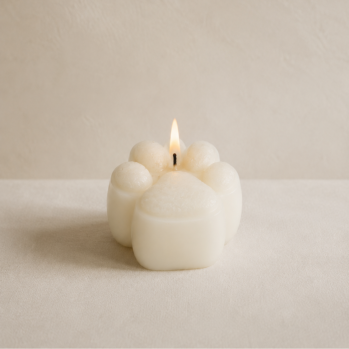 Vela decorativa huellita de perro y gato blanca encendida