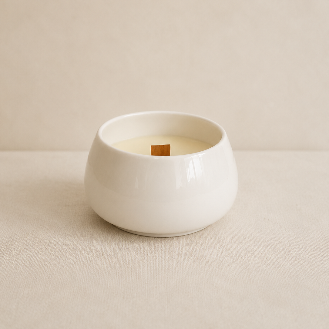 Vela aromática de soja en cuenco de porcelana blanca sobre fondo neutro