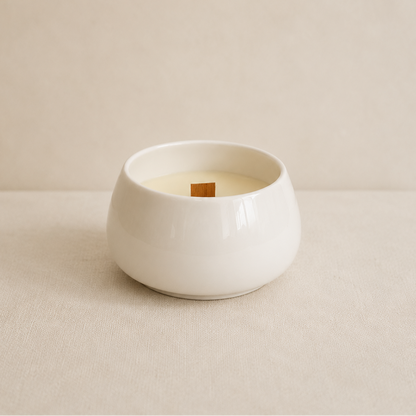 Vela aromática de soja en cuenco de porcelana blanca sobre fondo neutro