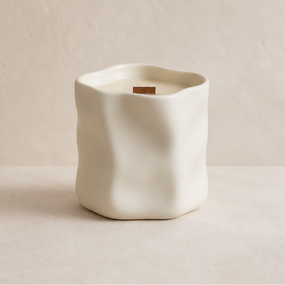 Vela aromática de soja en cerámica blanca irregular en composición minimalista
