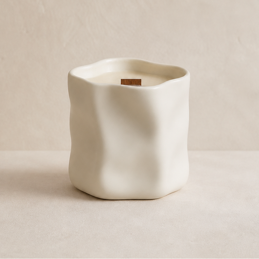 Vela aromática de soja en cerámica blanca irregular en composición minimalista