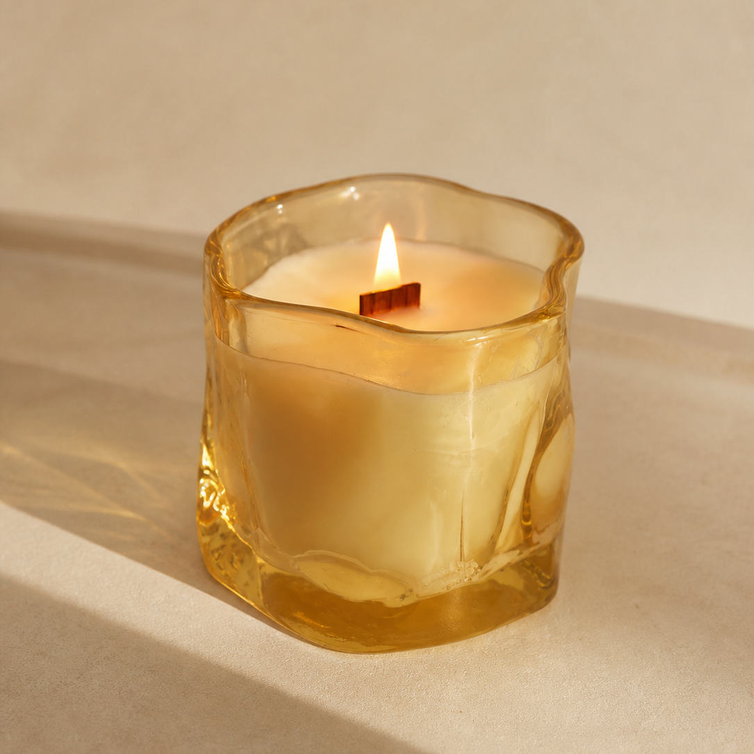 Detalle de vela aromática de soja en cristal irregular ámbar encendida