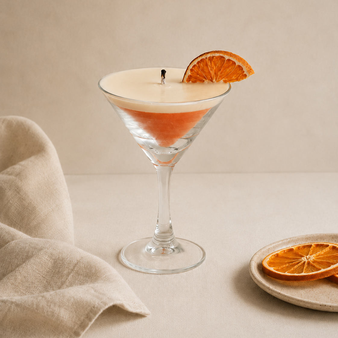 Vela aromática de soja en copa cóctel encendida con naranja deshidratada