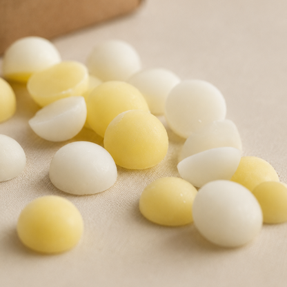 Detalle de wax melts en bolitas blancas y amarillas aroma coco y cítricos